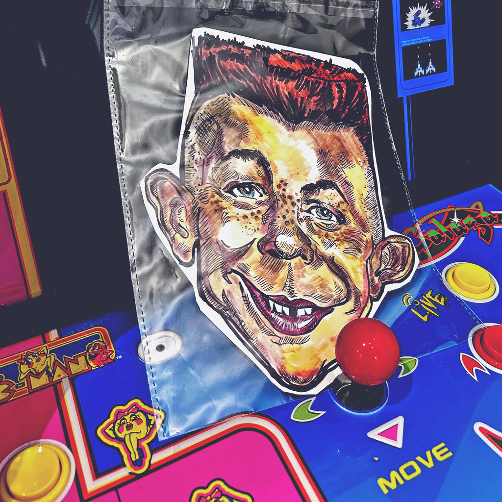 Alfred E Neuman Taxi Driver Mask, sitting on a Ms Pacman arcade video game